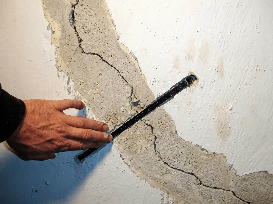 A wall with a large crack is being inspected by a professional in Anaheim, CA